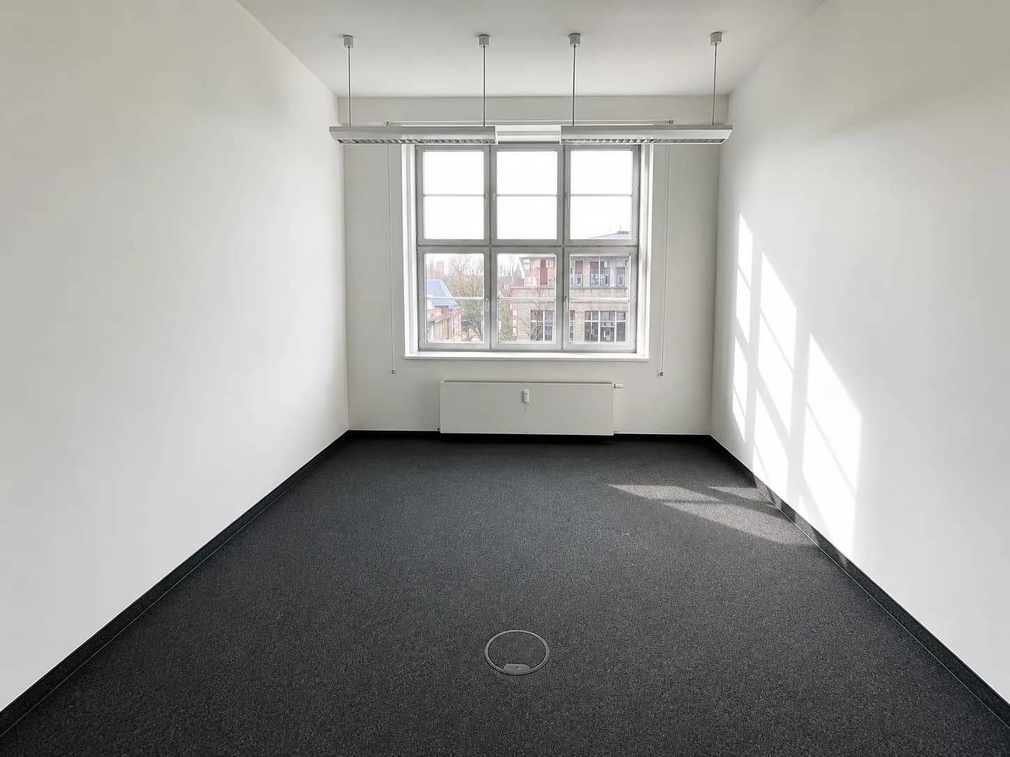 Helle Büroräume mit großen Fenstern und Teppichboden